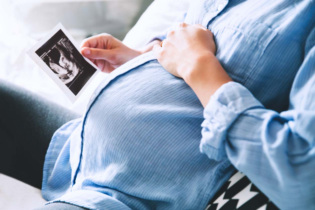 Close-up of a pregnant woman holding an ultrasound scan, representing a successful IVF pregnancy following embryo screening and genetic testing