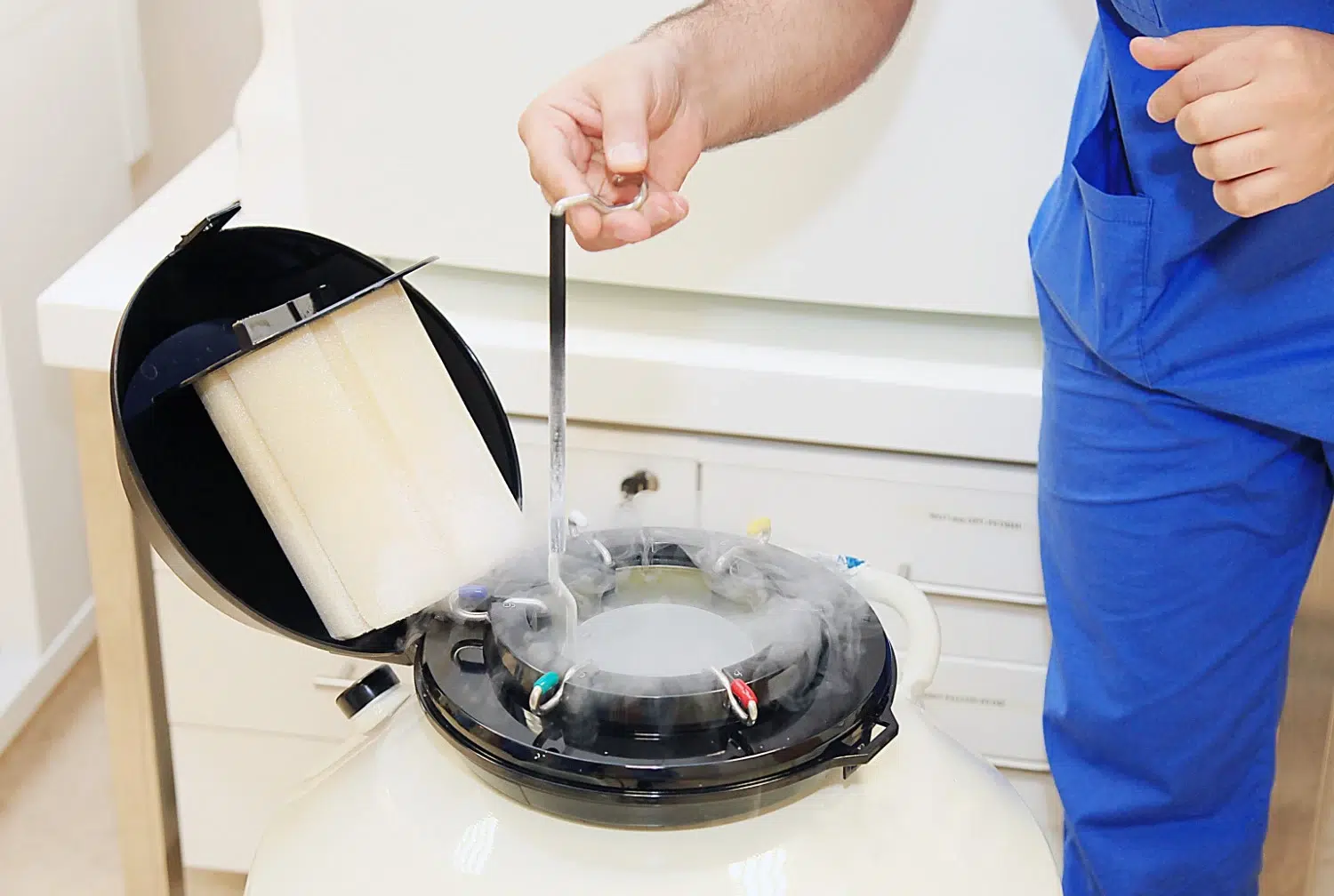 A fertility specialist handling a cryogenic storage tank filled with liquid nitrogen, used to safely freeze and store eggs during fertility preservation.