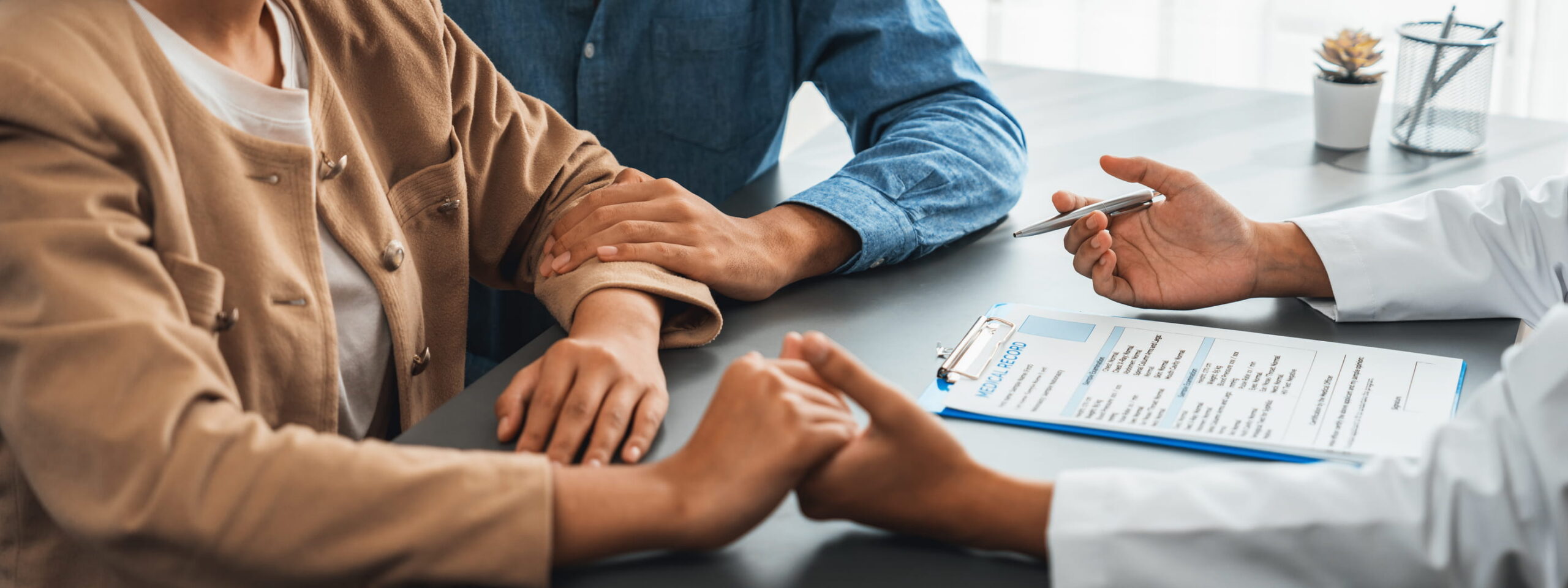 Um especialista em fertilidade discute as opções de tratamento de IIU e FIV com um casal durante uma consulta na clínica.